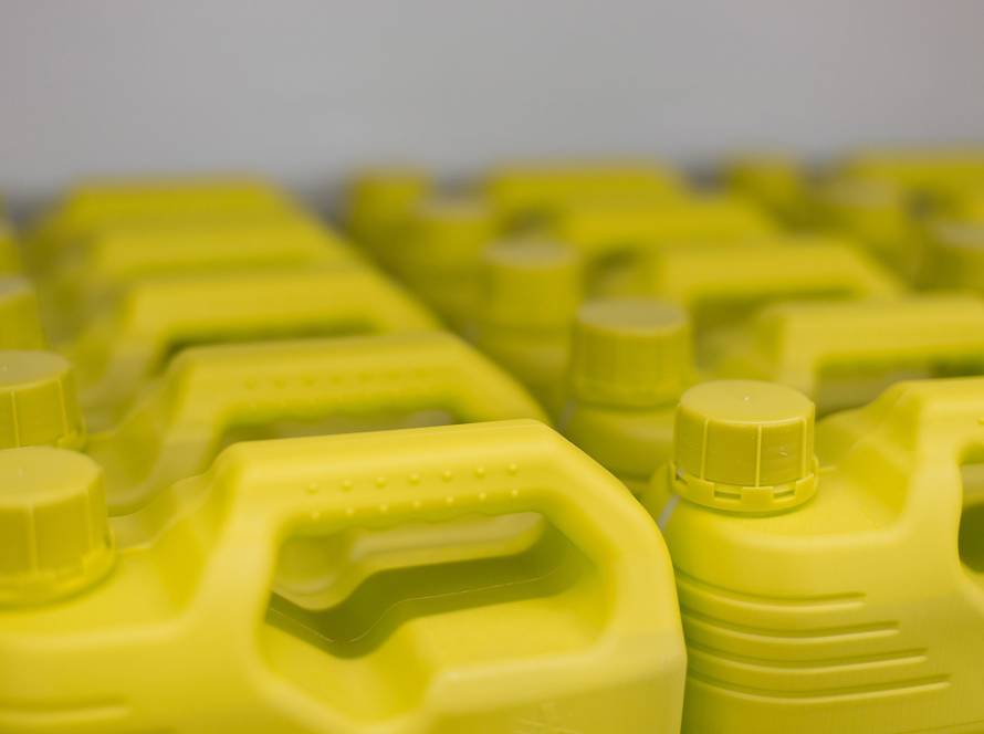 Close-up view of yellow plastic motor oil containers neatly arranged on a shelf in an auto service shop.